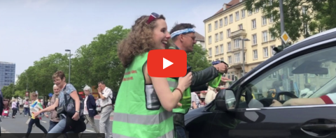Personen in grüner Weste vor einem Auto (Videobild)